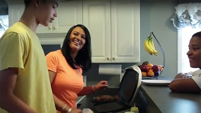 A mom prepares dinner with her kids using an electric grill.